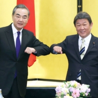 Foreign Minister Toshimitsu Motegi (right) greets his Chinese counterpart Wang Yi in Tokyo in November. | POOL / VIA KYODO