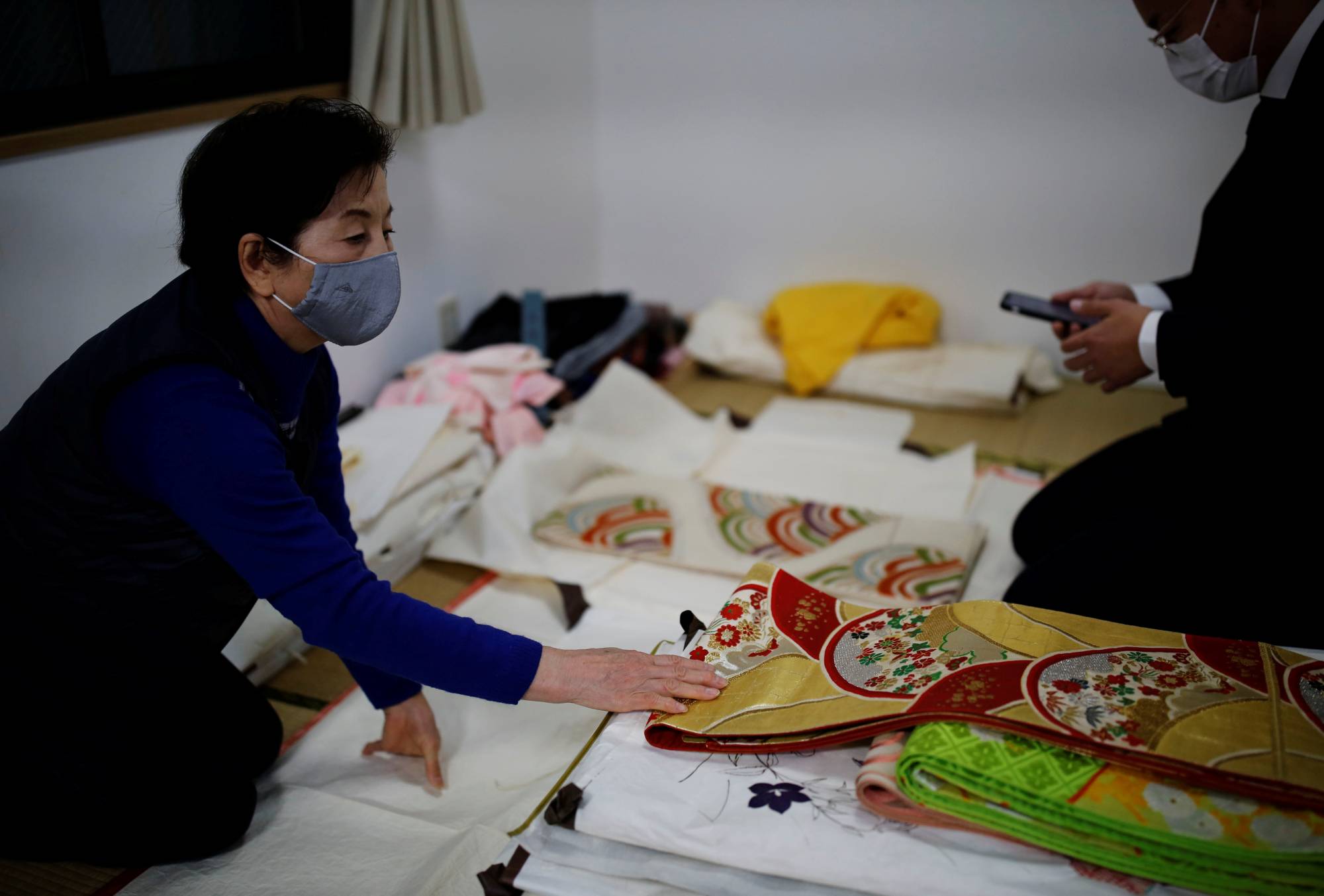 Mitsuko Iwama touches one of her kimono while a staffer of Buysell Technologies assesses them at her home in Tokyo on Dec. 5. | REUTERS