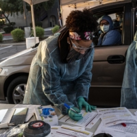 Health care workers at a COVID-19 drive-thru testing site at Grand Canyon University in Phoenix on Dec. 12. China stamped out the coronavirus, Communist Party messaging goes, with a resolve beyond the reach of flailing Western democracies. | ADRIANA ZEHBRAUSKAS / THE NEW YORK TIMES