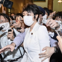 Upper House lawmaker Anri Kawai, the wife of former Japanese Justice Minister Katsuyuki Kawai, is surrounded by reporters after an Upper House plenary session in Tokyo on June 17. | KYODO