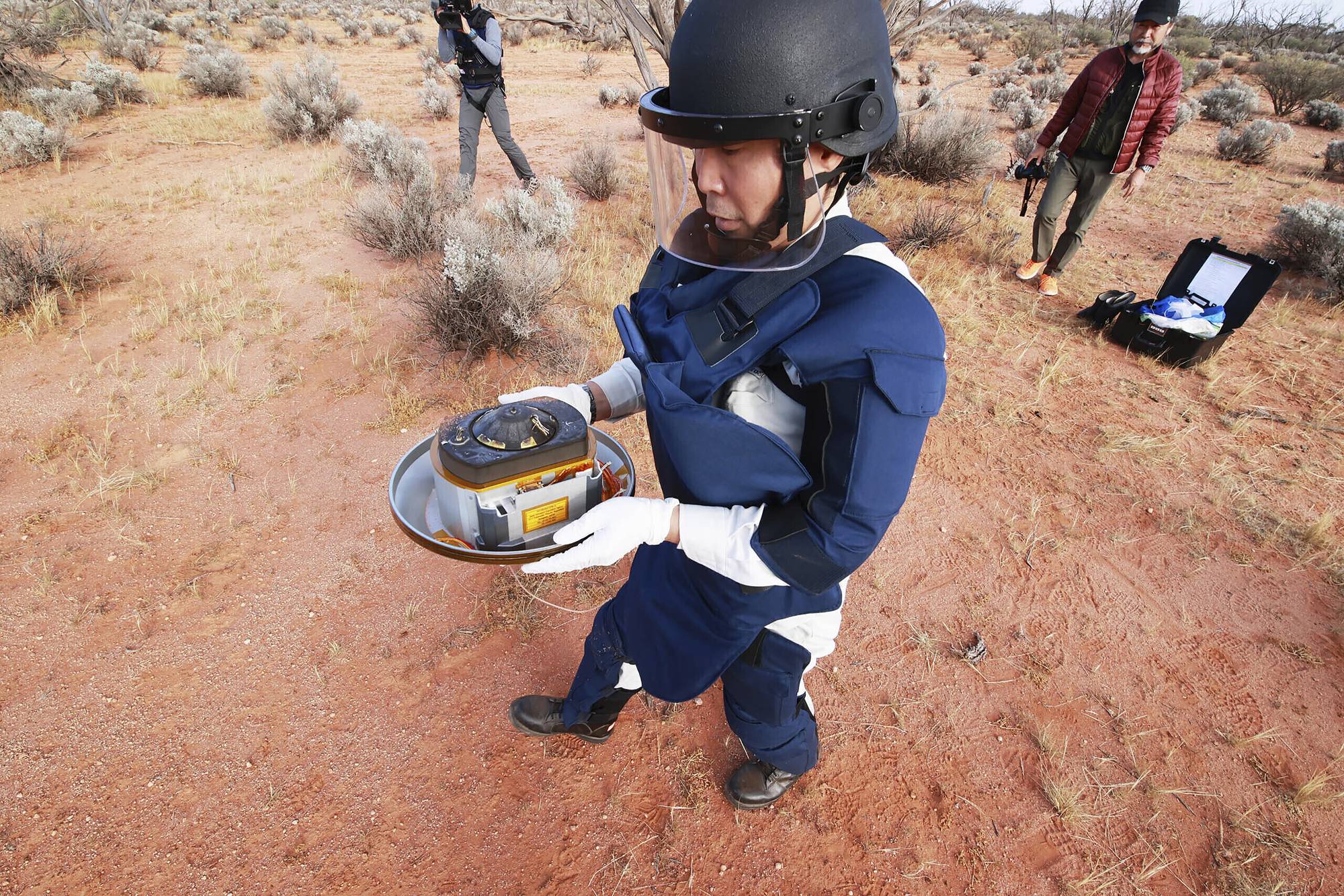 A member of the Japan Aerospace Exploration Agency retrieves a capsule dropped by Hayabusa2 in Woomera, southern Australia, on Dec. 6. | JAXA / VIA AP