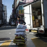 Park Ki-Ryeon delivers bags of rice to customers in Seongnam, a city on the outskirts of Seoul, late last month.  | WOOHAE CHO / THE NEW YORK TIMES