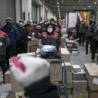 Couriers raise their fists while singing a union song at a depot in Seoul. More than a dozen couriers have died this year, some after complaining of unbearable workloads that kept them on the clock from dawn until past midnight. | WOOHAE CHO / THE NEW YORK TIMES