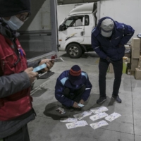 Couriers check delivery addresses at a distribution center in Seoul on Nov. 30.  | WOOHAE CHO / THE NEW YORK TIMES