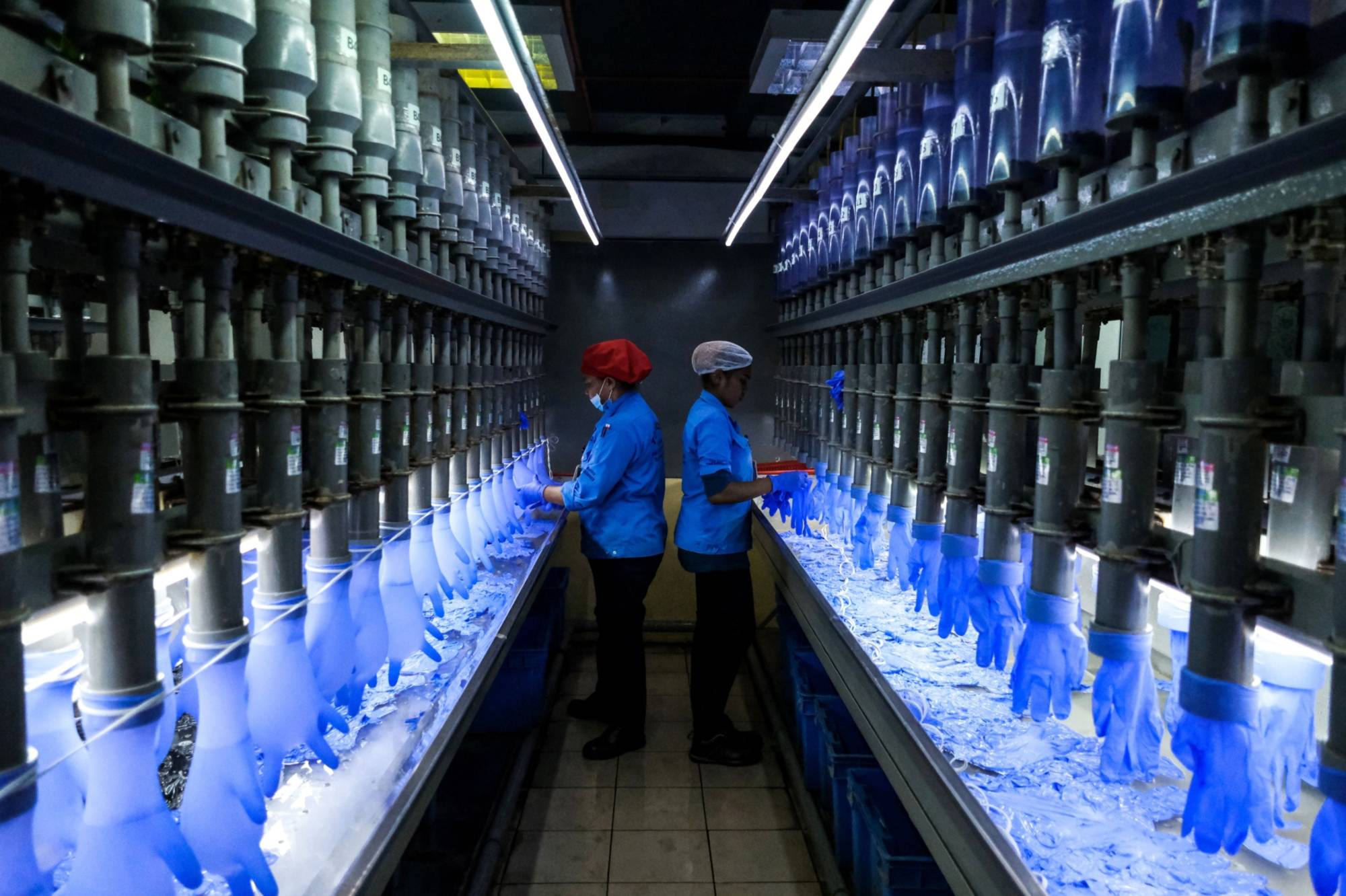 Employees check latex gloves in the watertight test room at a Top Glove Corp. factory in Setia Alam, Selangor, Malaysia, on Feb. 18. | BLOOMBERG