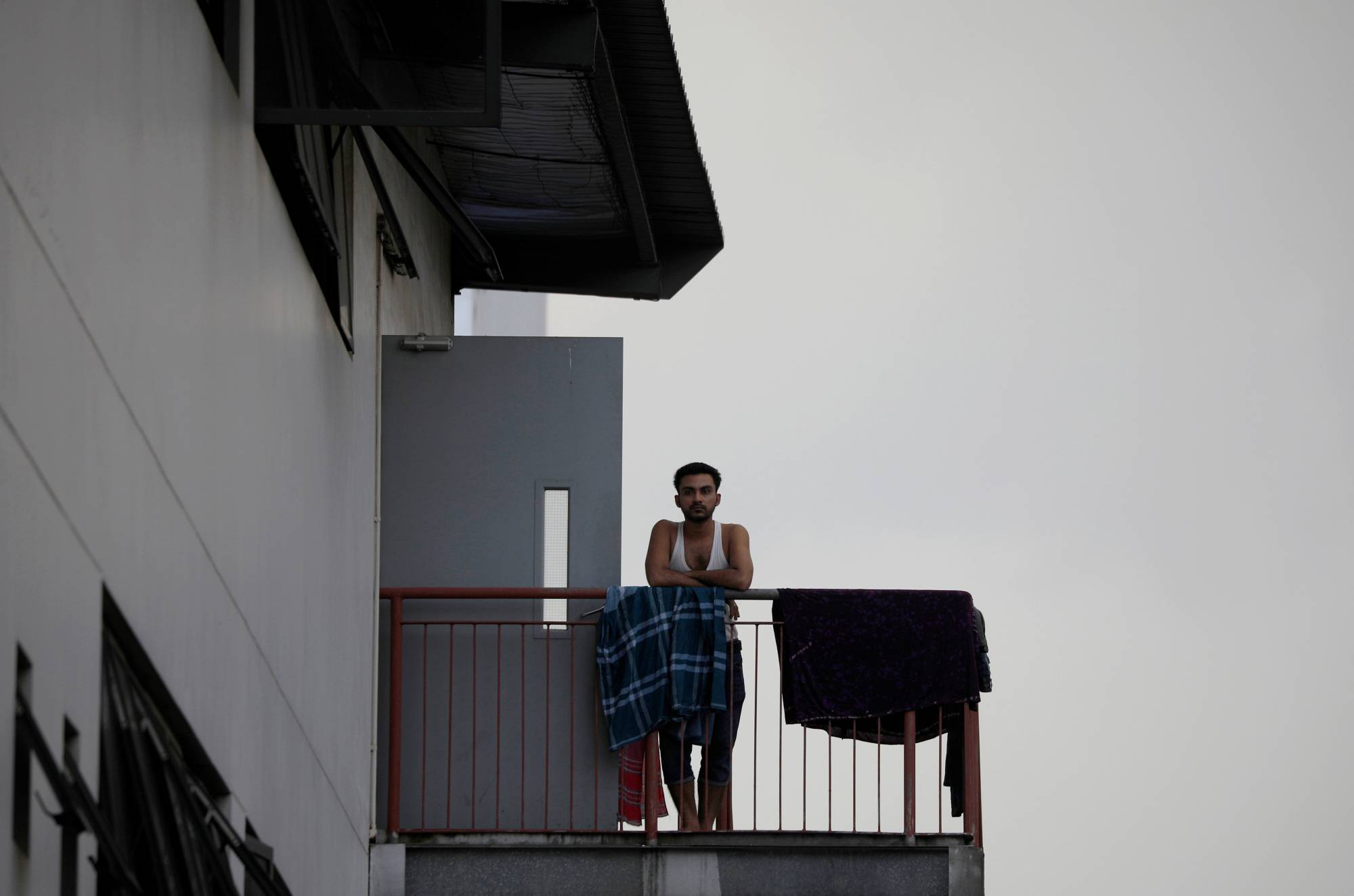 A migrant worker looks on from outside his room in a factory-converted dormitory in Singapore in May. | REUTERS