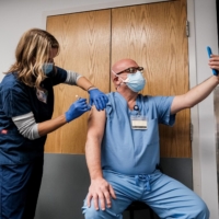 A health care worker makes a selfie while receiving a Pfizer-BioNTech COVID-19 vaccine at Virginia Hospital Center in Arlington on Wednesday.  | MICHAEL A. MCCOY/THE NEW YORK TIMES