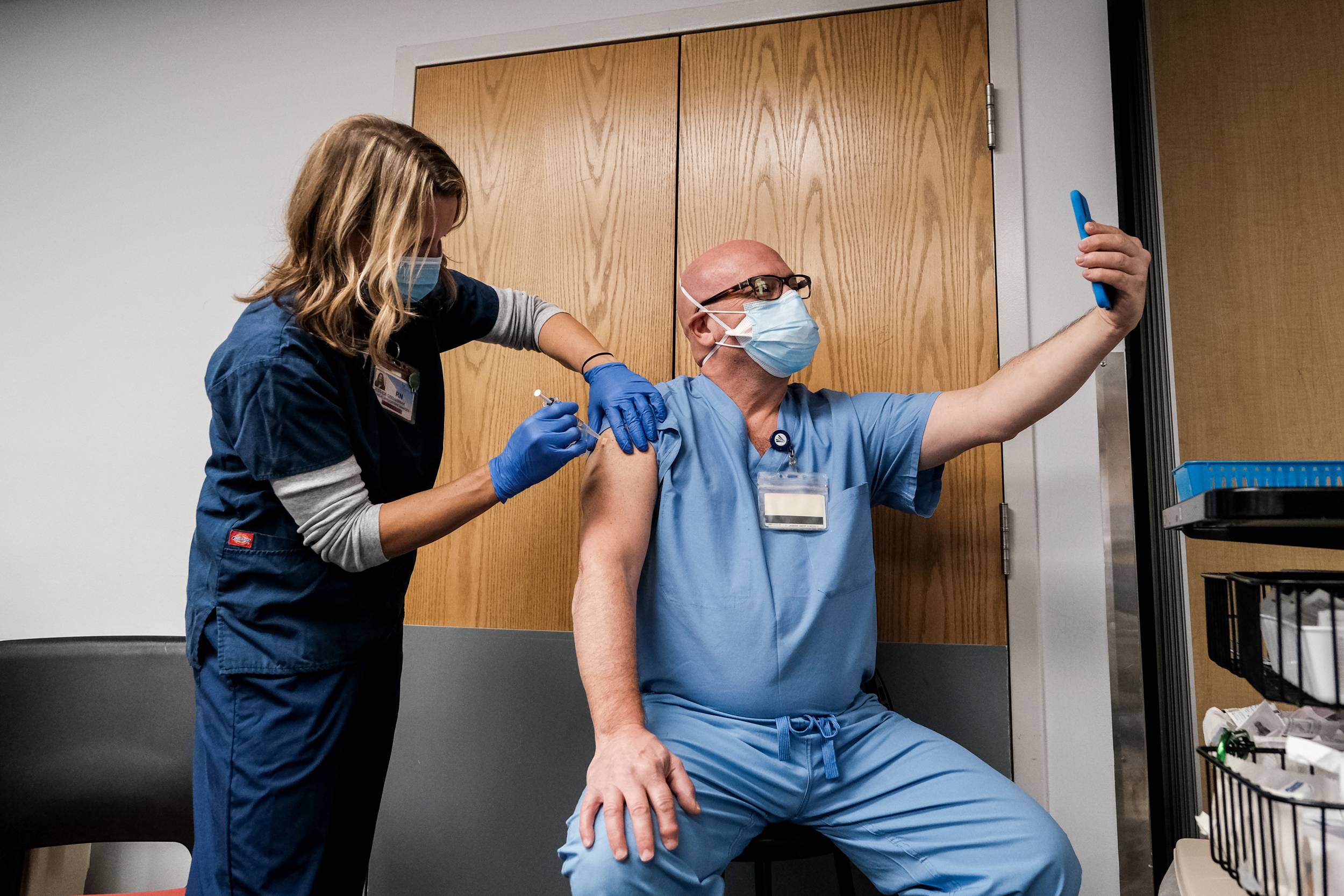 A health care worker makes a selfie while receiving a Pfizer-BioNTech COVID-19 vaccine at Virginia Hospital Center in Arlington on Wednesday. | Michael A. McCoy/The New York Times