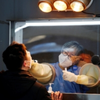 A man undergoes a COVID-19 test at at a temporary site at City Hall Plaza in Seoul on Friday. | REUTERS