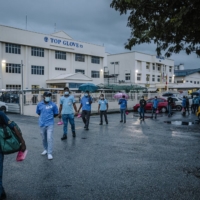 Top Glove employees leave after a shift at the company\'s factory in Klang, Malaysia, on Dec. 14. | THE NEW YORK TIMES