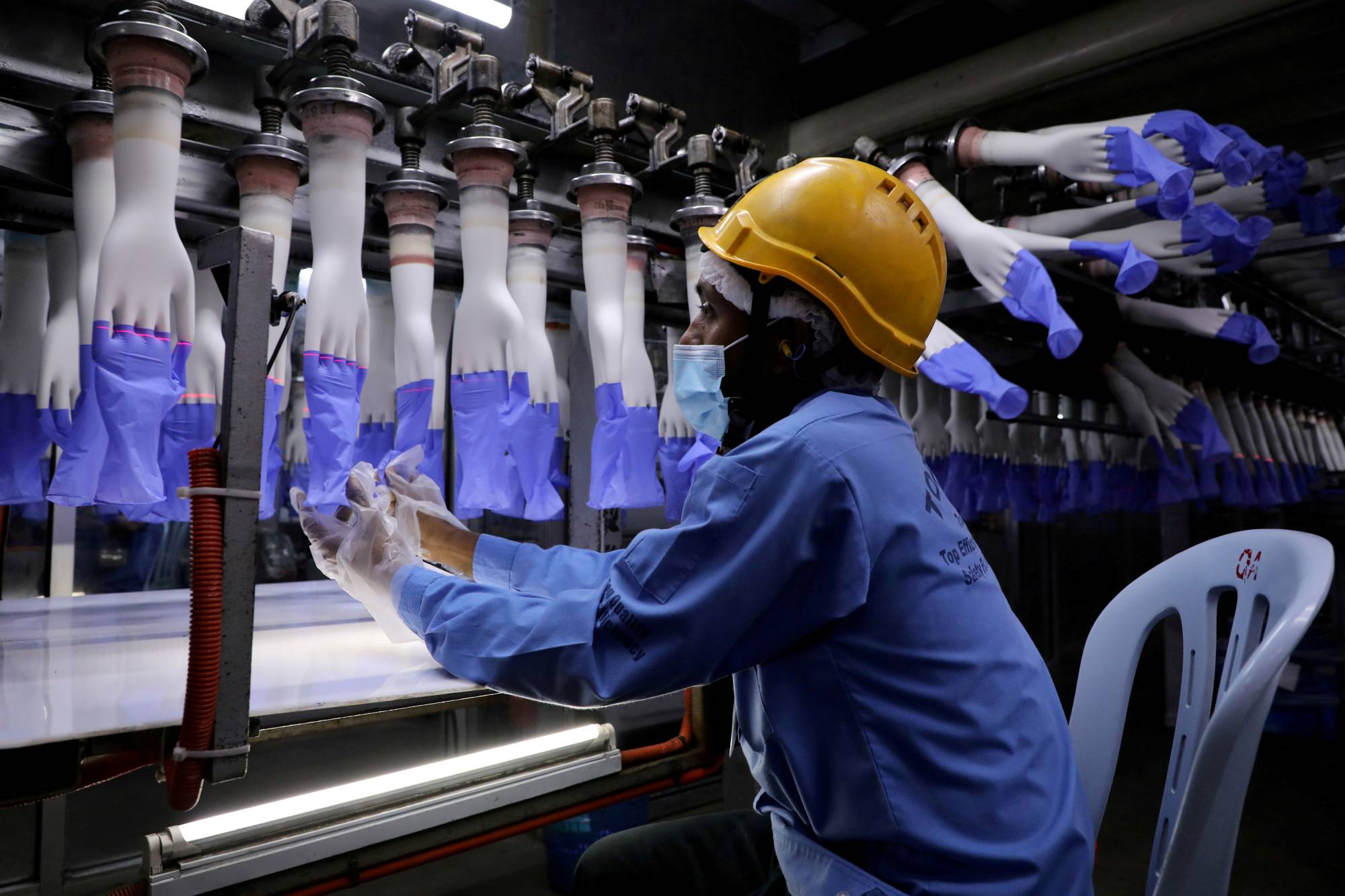 A worker inspects gloves at the Top Glove factory in Shah Alam, Malaysia, in August. | Reuters 