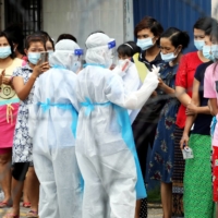 Top Glove workers wait to be tested for COVID-19 outside a hostel in Klang, Malaysia, in November. | REUTERS 
