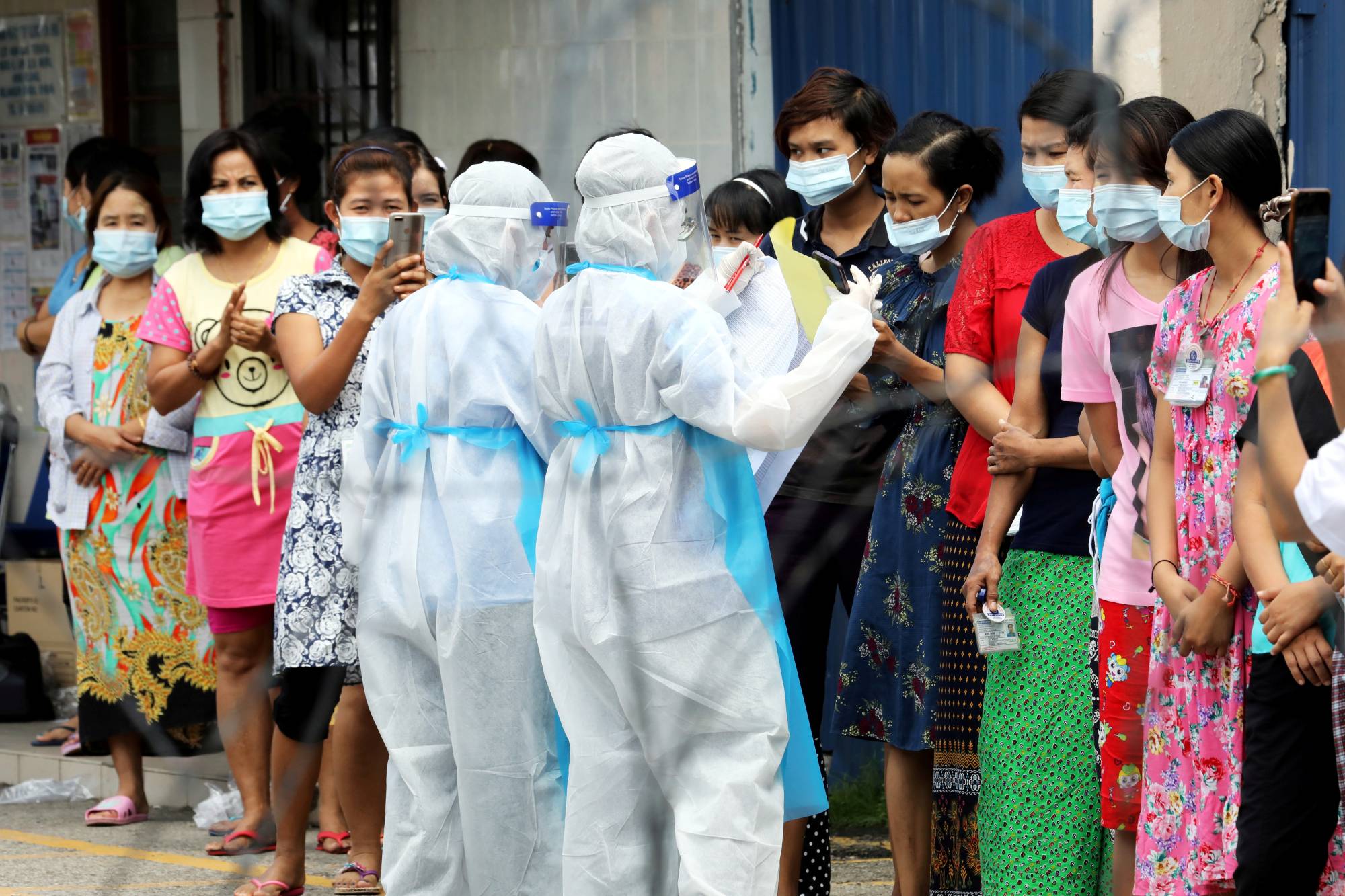Top Glove workers wait to be tested for COVID-19 outside a hostel in Klang, Malaysia, in November. | Reuters 
