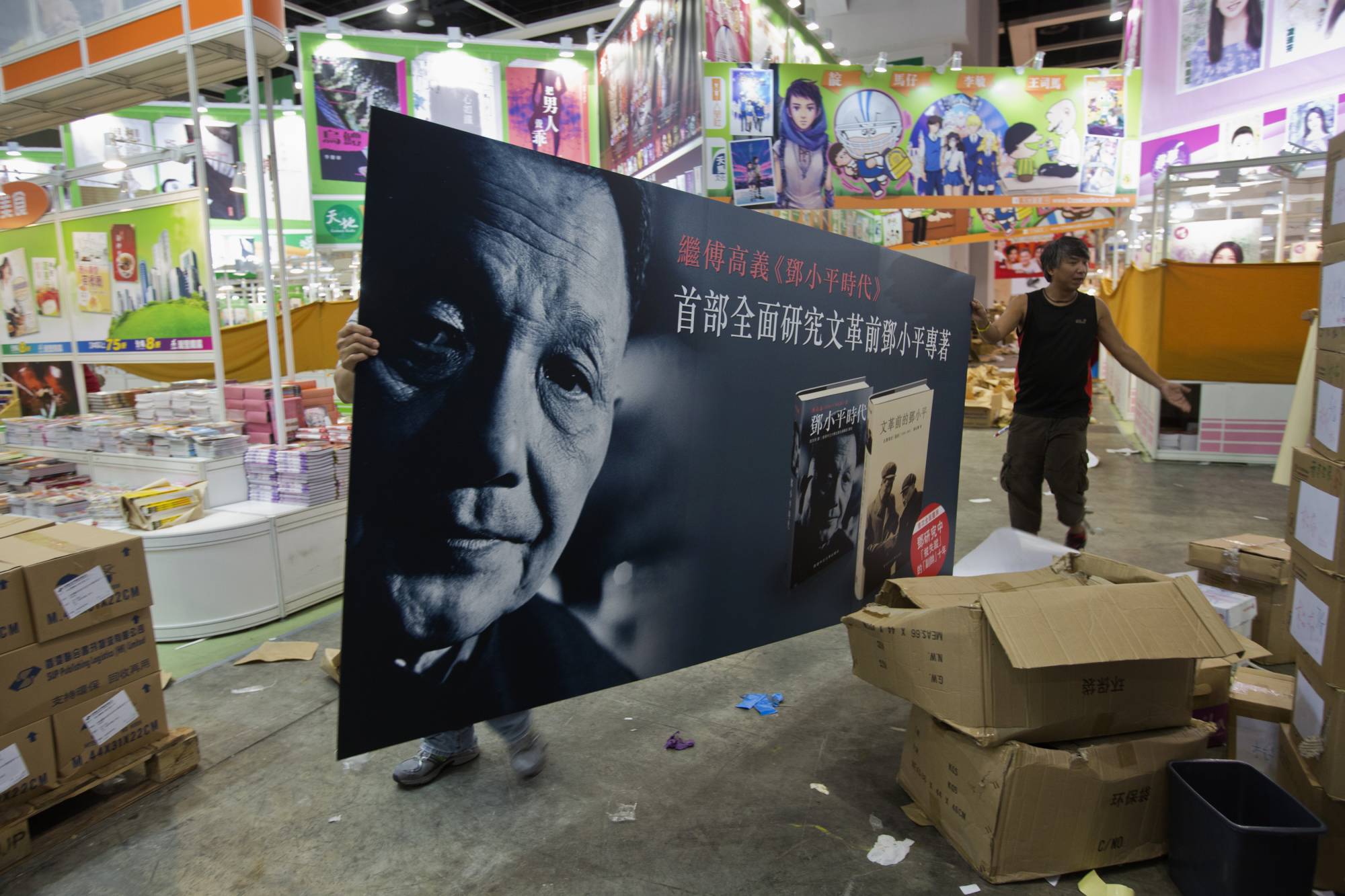 Workers carry an advertisement promoting the Chinese edition of 'Deng Xiaoping and the Transformation of China', written by Harvard University Professor Emeritus Ezra Vogel, during a media preview of the Hong Kong Book Fair in 2013. | REUTERS 