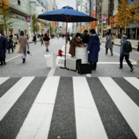 A shopper washes her hands using a mobile handwashing machine called Wosh, installed to prevent the spread of COVID-19, in the Ginza shopping district of Tokyo on Saturday. | REUTERS