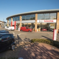 Parked cars block the entrance to a closed Toyota Motor Corp. dealership in London on April 20. Toyota will halt production in the U.K. and France from Tuesday due to transport delays caused by a mutant strain of coronavirus. | BLOOMBERG