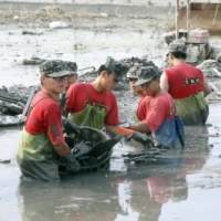 Soldiers pick up rubbish and items on a flooded street following Typhoon Morakot in Pingtung County, southern Taiwan, on August 23, 2009. | TAIWAN MILITARY NEWS AGENCY / VIA REUTERS