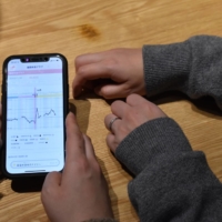 A transgender man (right) and his wife use a smartphone app in Tokyo to estimate the timing of their next ovulation date, which they ensure will coincide with their visit to a sperm donor they have matched up with on social media. | TOMOHIRO OSAKI
