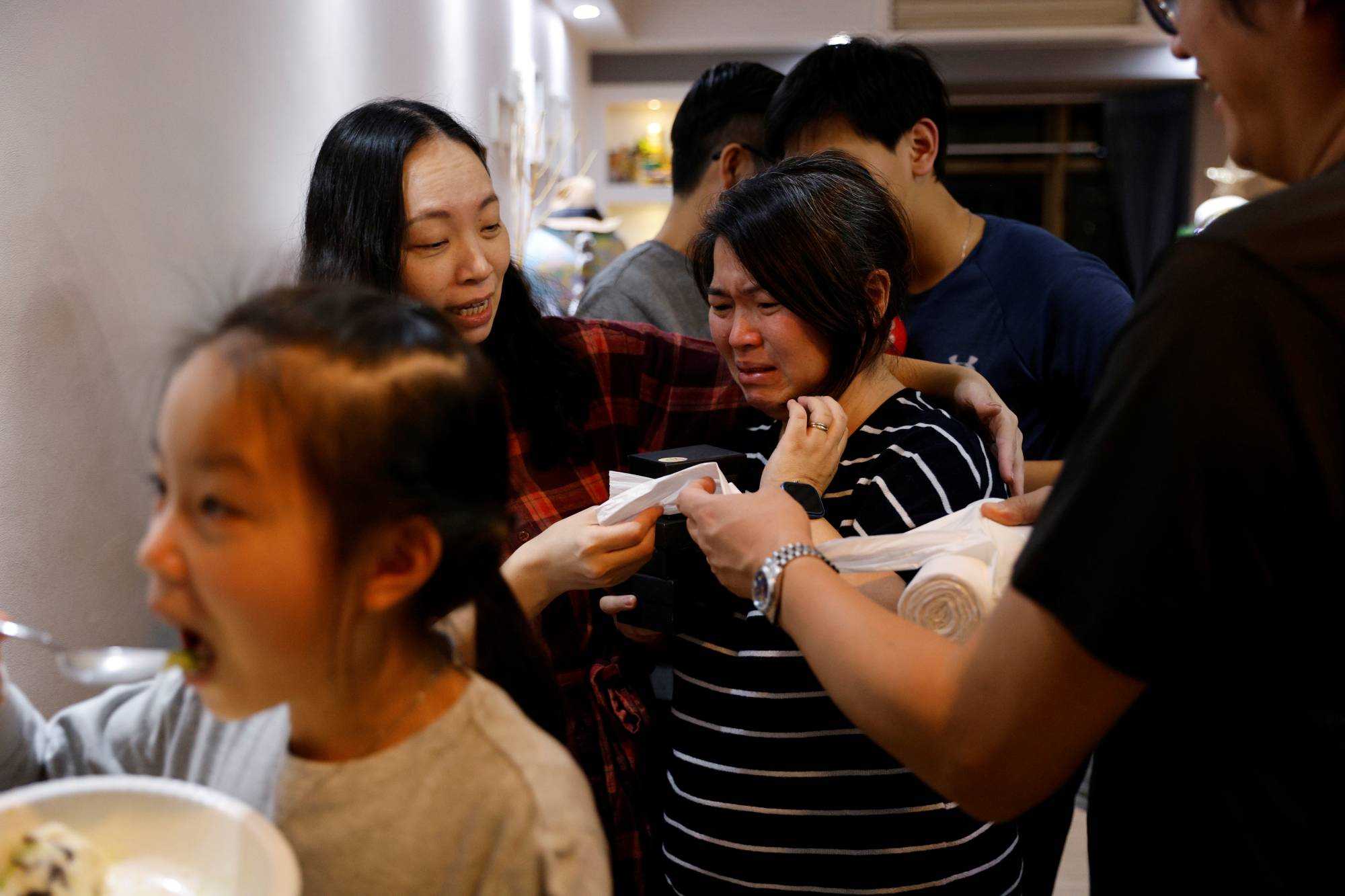 Asa Lai cries next to her friend during a farewell party for the Lai family before they emigrate to Scotland, at a friend's home in Hong Kong on Dec. 5. | REUTERS 
