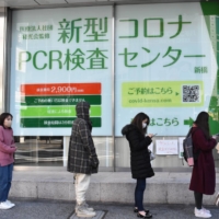 People form a line Wednesday in front of a private testing center that offers low-cost PCR testing for COVID-19 in the Shimbashi district of Tokyo. | TOMOHIRO OSAKI
