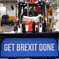 British Prime Minister and Conservative Party leader Boris Johnson drives a Union flag-themed JCB through a fake wall emblazoned with the word \"Gridlock\" at a general election campaign event in Uttoxeter, England, last December. | AFP-JIJI