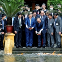 Prime Minister Yoshihide Suga and his Vietnamese counterpart, Nguyen Xuan Phuc, feed the fish by a pond at the Presidential Palace compound in Hanoi in October.  | POOL / VIA REUTERS 