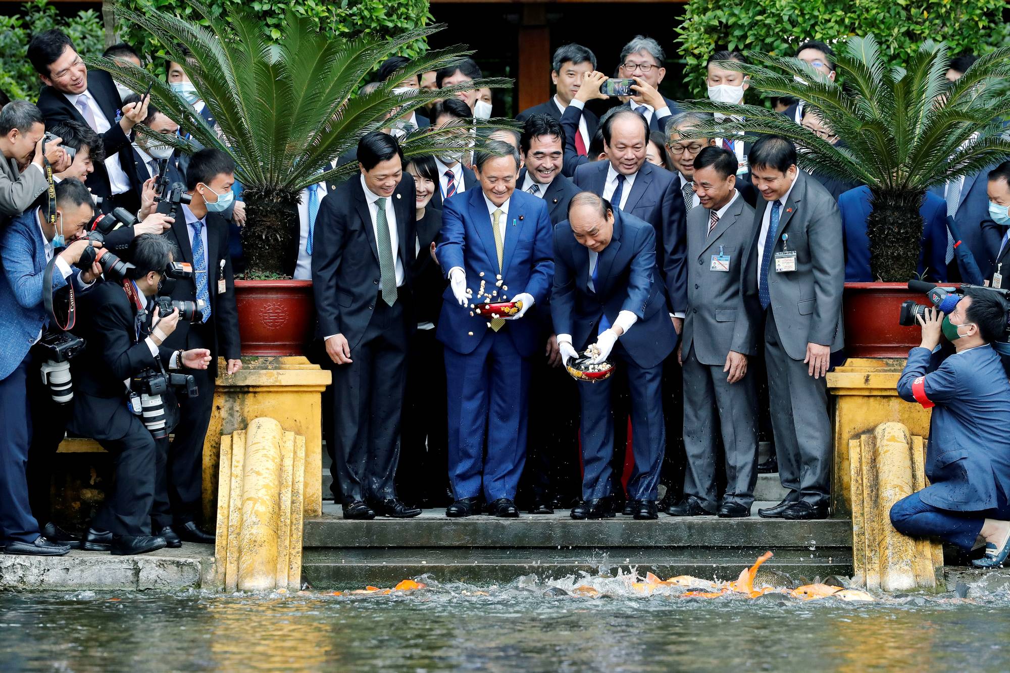 Prime Minister Yoshihide Suga and his Vietnamese counterpart, Nguyen Xuan Phuc, feed the fish by a pond at the Presidential Palace compound in Hanoi in October. | Pool / via Reuters 