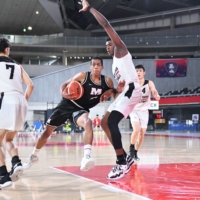 Meisei\'s Ibu Yamazaki (second from left) attacks the basket while being defended by Higashiyama center Jean Pierre Mutombo on Tuesday at Tokyo Metropolitan Gymnasium. | COURTESY OF THE JAPAN BASKETBALL ASSOCIATION
