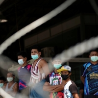 Migrant workers stand in front of a closed shrimp market in Samut Sakhon province, Thailand, on Dec. 20.  | REUTERS