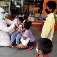A health care worker takes a nasal swab sample of a child for a COVID-19 test at a migrant community in Samut Sakhon province, Thailand, on Dec. 20.   | REUTERS