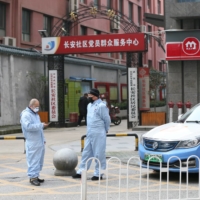 Taxi drivers use protective suits in front of a residential area of Wuhan in January.  | CHINA DAILY / VIA REUTERS 