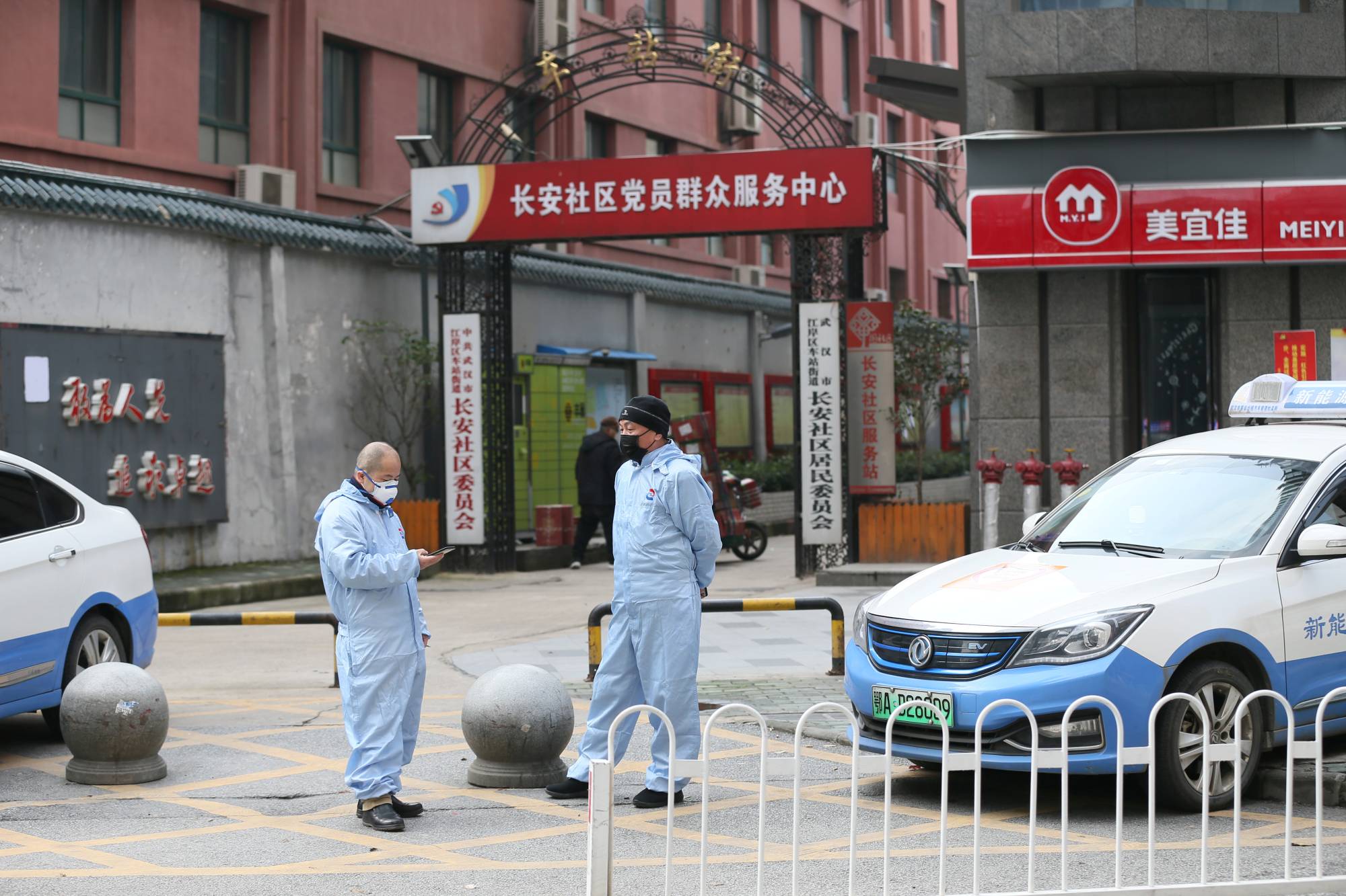 Taxi drivers use protective suits in front of a residential area of Wuhan in January. | China Daily / via REUTERS 