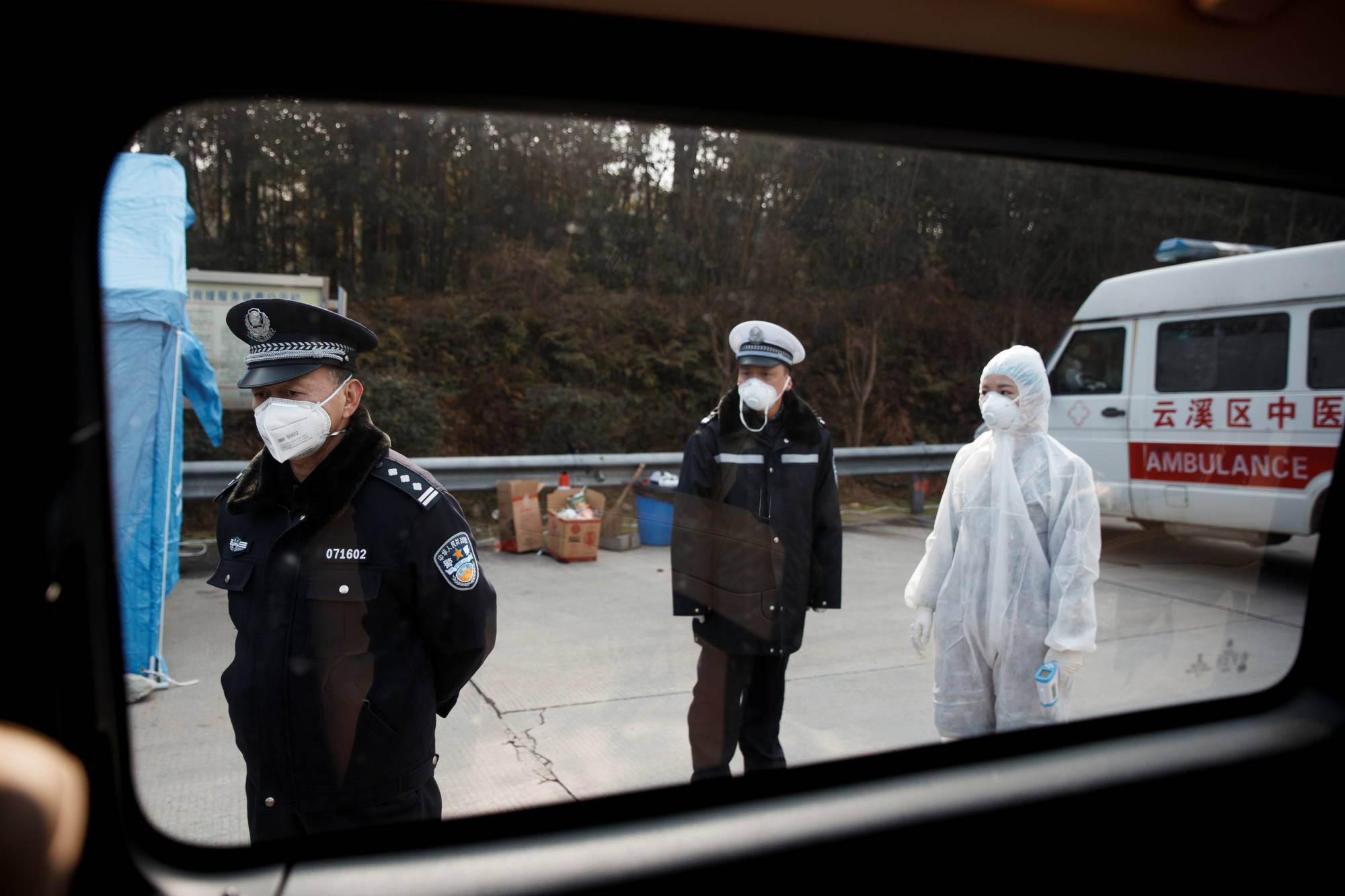 A medical worker and police wait for drivers at a checkpoint in Yunxi county, in China's Hunan province, near the border to Hubei province, amid lockdowns in January. | Reuters 