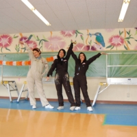 Clara Campos (left), Teresa Currea (center) and Oriana Marin (right) celebrate the completion of a mural inside a community center in the city of Kofu, in Yamanashi Prefecture. | COURTESY OF KOFU CITY
