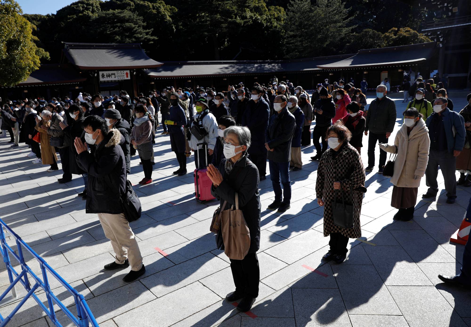 People wearing protective masks pray on the first day of the new year at Tokyo's Meiji Shrine on Friday. | REUTERS