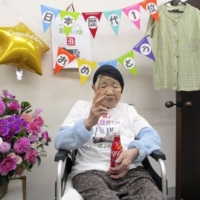 Kane Tanaka poses for a photo after setting an all-time Japanese age record in September last year at 117 years and 261 days. Tanaka celebrated her 118th birthday in the city of Fukuoka on Saturday. | TANAKA FAMILY / VIA KYODO
