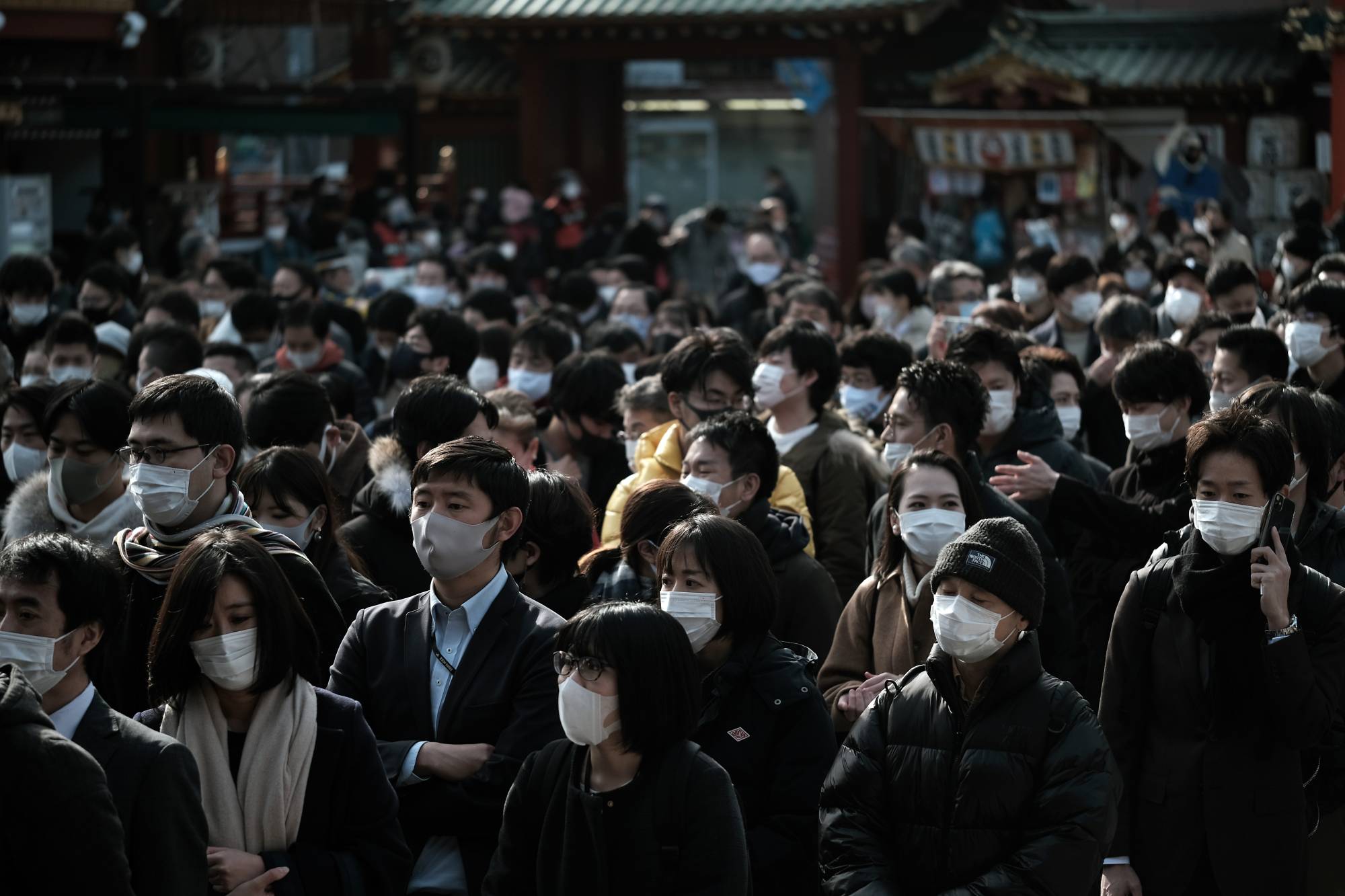 People wearing protective face masks as they line up to offer prayers on the first business day of the year at the Kanda Myojin shrine in Tokyo on Monday. | BLOOMBERG