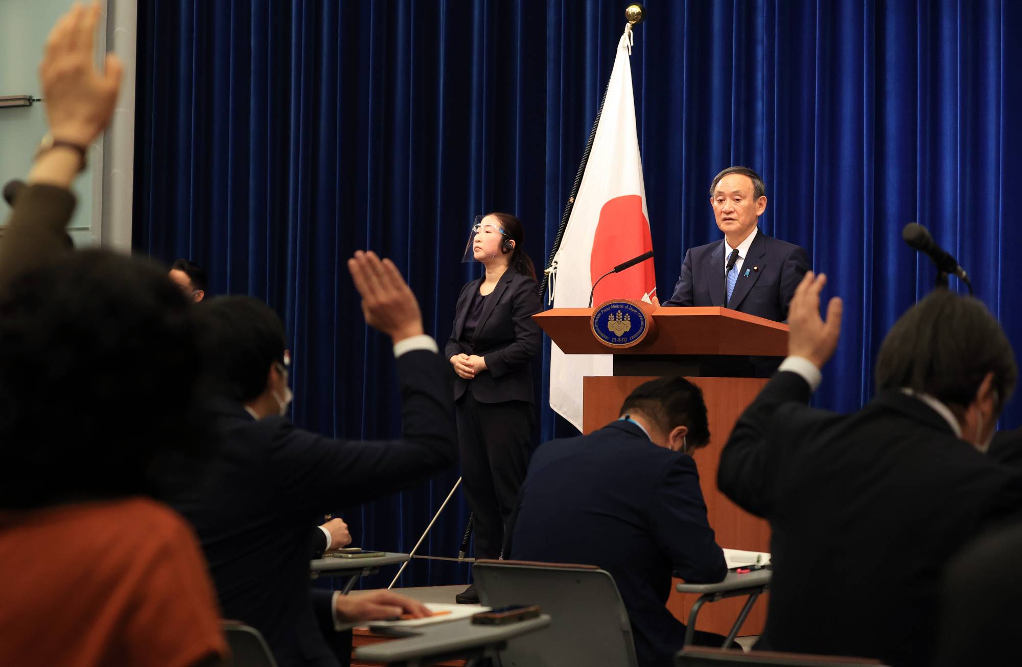 Journalists raise their hands to ask questions of Prime Minister Yoshihide Suga during a news conference at the Prime Minister's Office in Tokyo on Monday. | BLOOMBERG