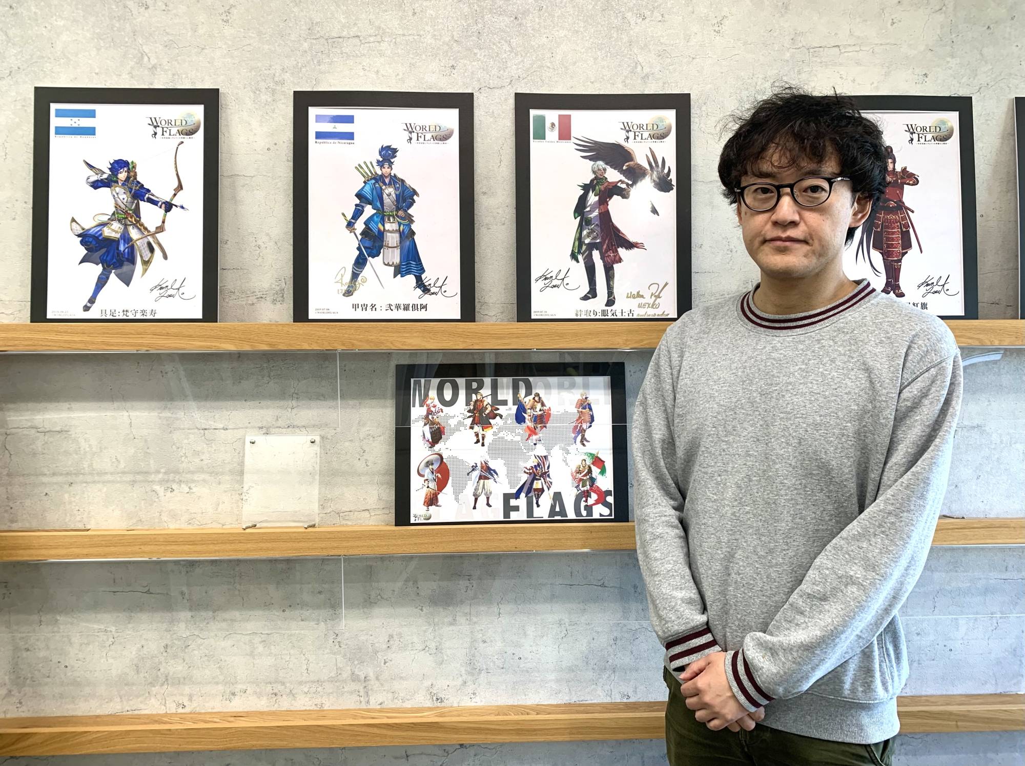 Fly the flag: Kozo Yamada, public relations officer at Digital Entertainment Asset Pte. Ltd., which works with the World Flags project, stands in front of some of the framed illustrations in their office in Tokyo.  | KYODO