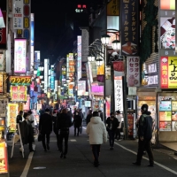 Pedestrians walk on a street in the Shinjuku area of Tokyo on Tuesday. | AFP-JIJI