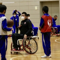 Yasuhiro Jimbo demonstrates the specialized equipment used for wheelchair basketball to students at Yokoshibahikari Junior High School in Chiba Prefecture during a December 2020 event hosted by the Nippon Foundation Paralympic Support Center. | KAZ NAGATSUKA
