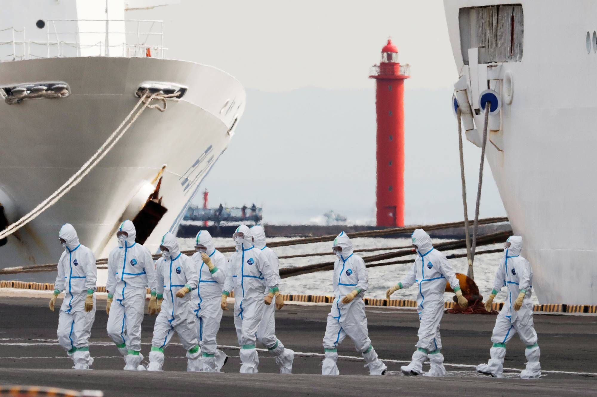 Workers wear protective gear to protect them against the COVID-19 virus near the cruise ship Diamond Princess at Daikoku Pier Cruise Terminal in Yokohama last February. More than 700 of the 3,711 people on board the ship became infected with the virus, with 14 deaths being reported. |  REUTERS