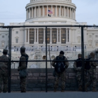 Members of the National Guard stand behind security fencing at the U.S. Capitol in Washington on Thursday.  | BLOOMBERG
