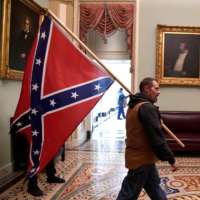A supporter of President Donald Trump carries a Confederate battle flag on the second floor of the U.S. Capitol near the entrance to the Senate after breaching security defenses, in Washington on Wednesday. | REUTERS