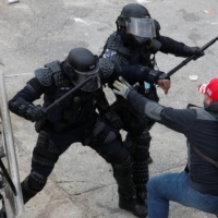 Police officers wield their batons against a man as pro-Trump rioters storm into the U.S. Capitol on Wednesday.  | REUTERS 