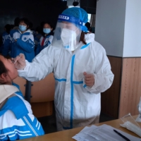 A medical worker collects a swab sample from a middle school student during mass nucleic acid testing following a recent coronavirus outbreak in Xingtai, Hebei province, China, on Wednesday. | CHINA DAILY / VIA REUTERS
