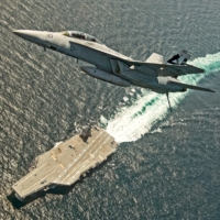 An F/A-18F Super Hornet jet flies over the USS Gerald R. Ford in the Atlantic Ocean in July 2017. | U.S. NAVY / VIA REUTERS
