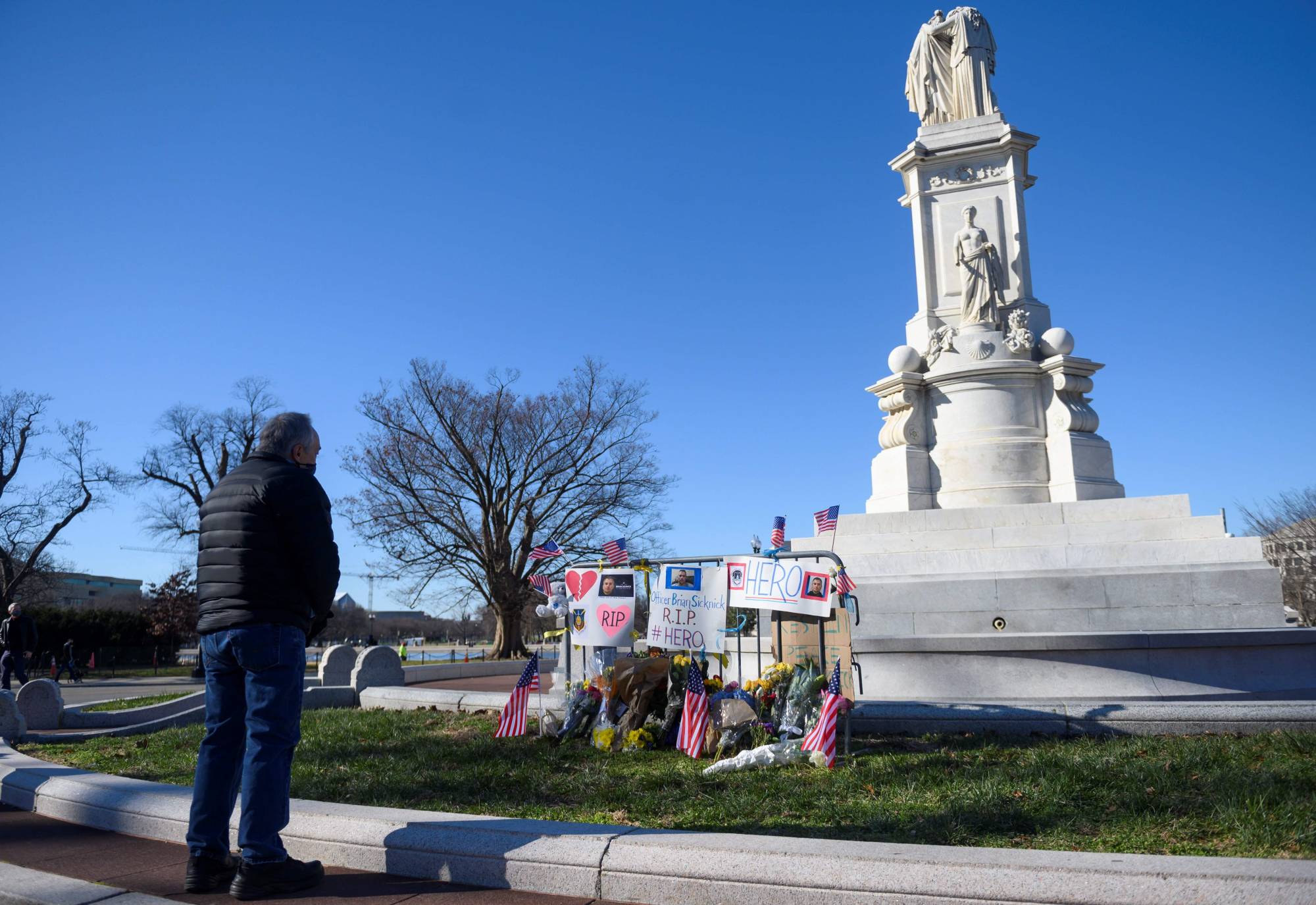 People pay their respects at a memorial for a fallen police officer, Brian Sicknick, in Washington on Monday. Sicknick was reportedly struck in the head with a fire extinguisher while struggling with the rioters who swarmed through the halls of Congress last Wednesday. | AFP-Jiji
