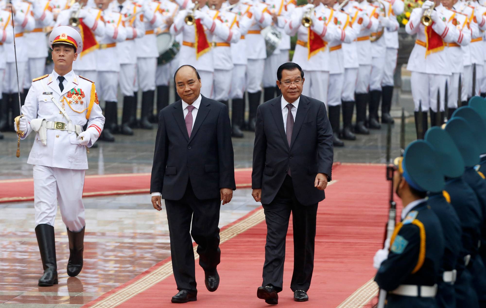 Cambodian Prime Minister Hun Sen (right) reviews an honor guard with his Vietnamese counterpart, Nguyen Xuan Phuc, in Hanoi, in October 2019.   |  REUTERS