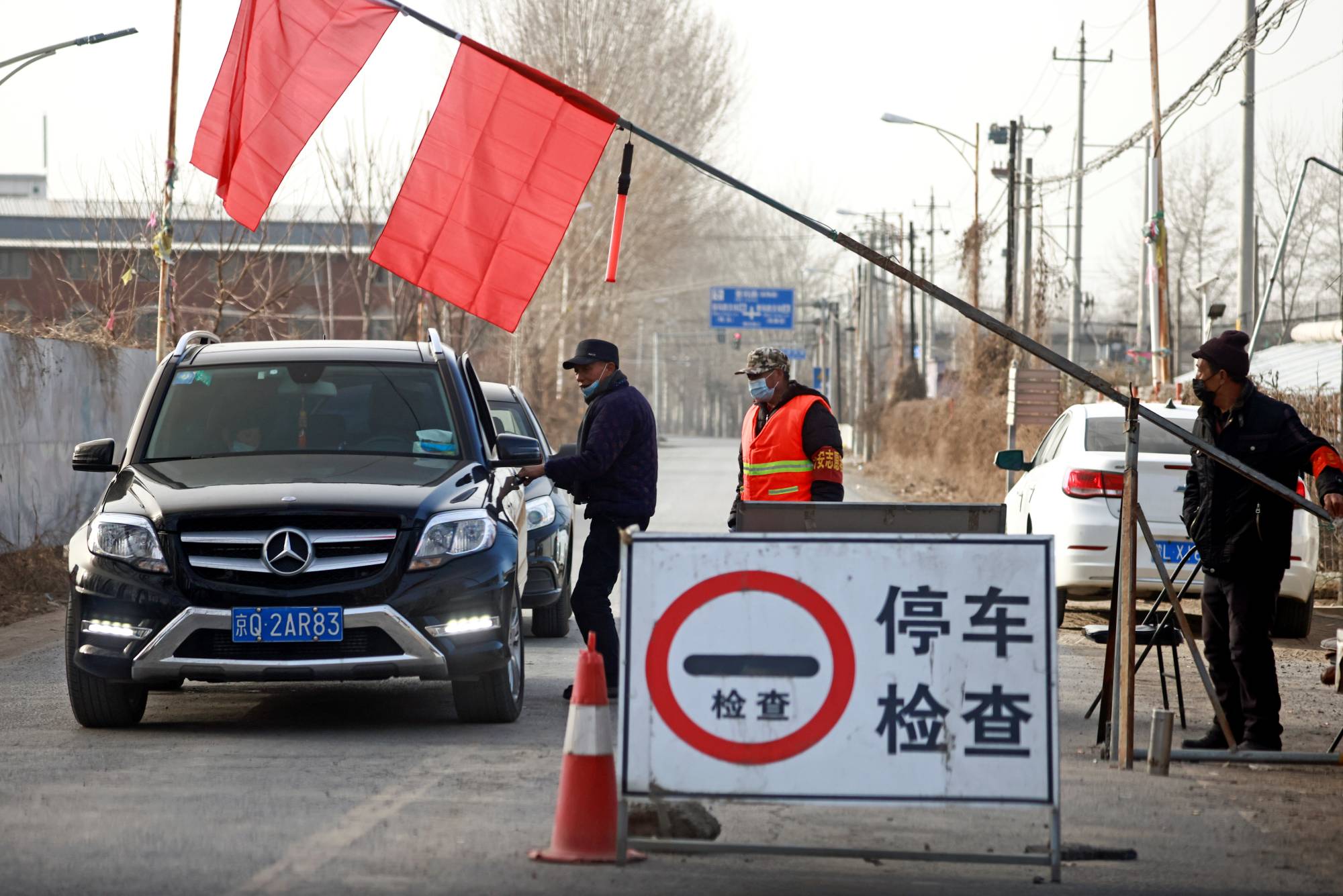 Volunteers stop a car at a checkpoint on the outskirts of Beijing amid a coronavirus outbreak on Tuesday.  | REUTERS